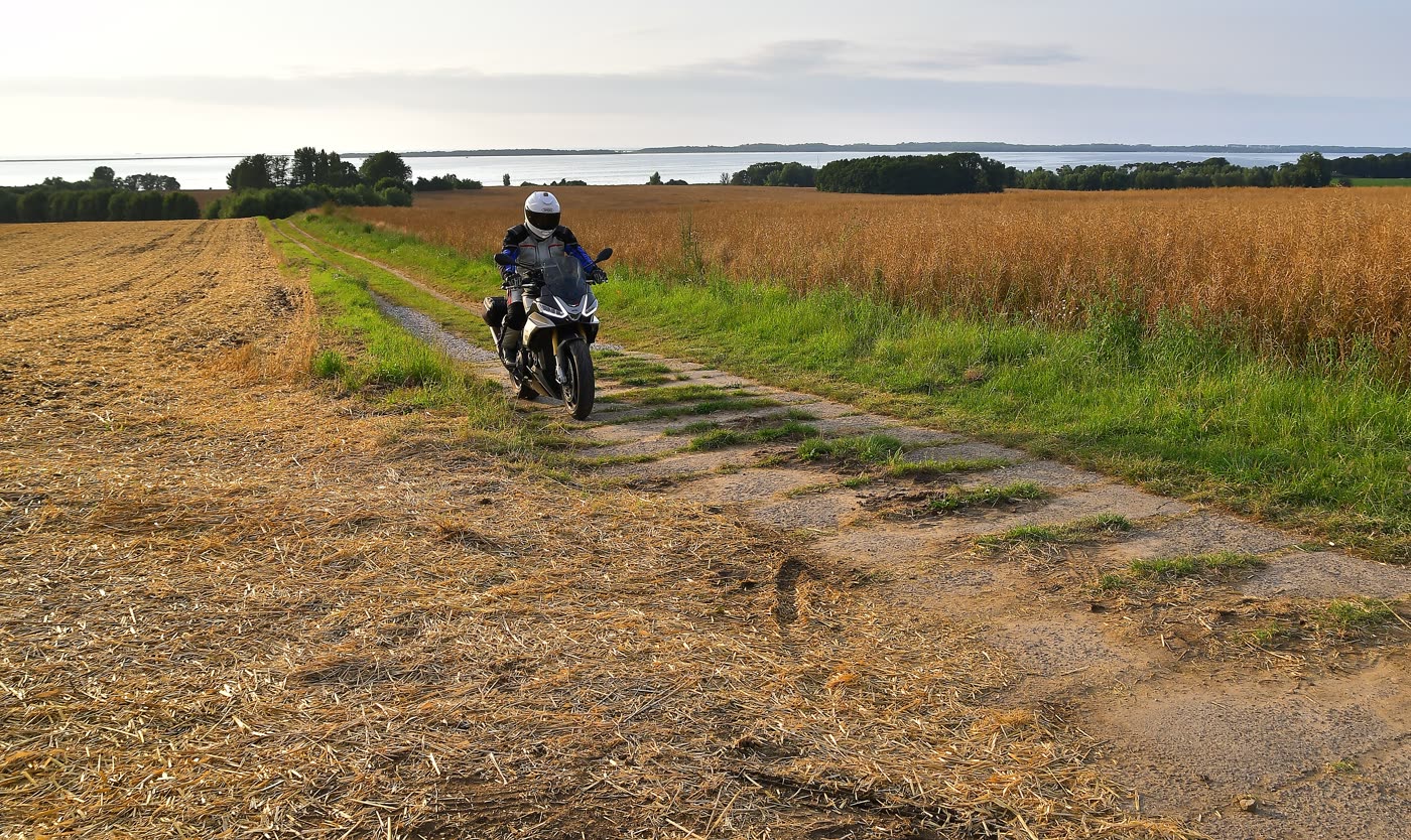 Motorrad auf einem Feldweg zwischen reifem Getreide nahe der Küste Motorrad auf einem Feldweg zwischen reifem Getreide nahe der Küste
